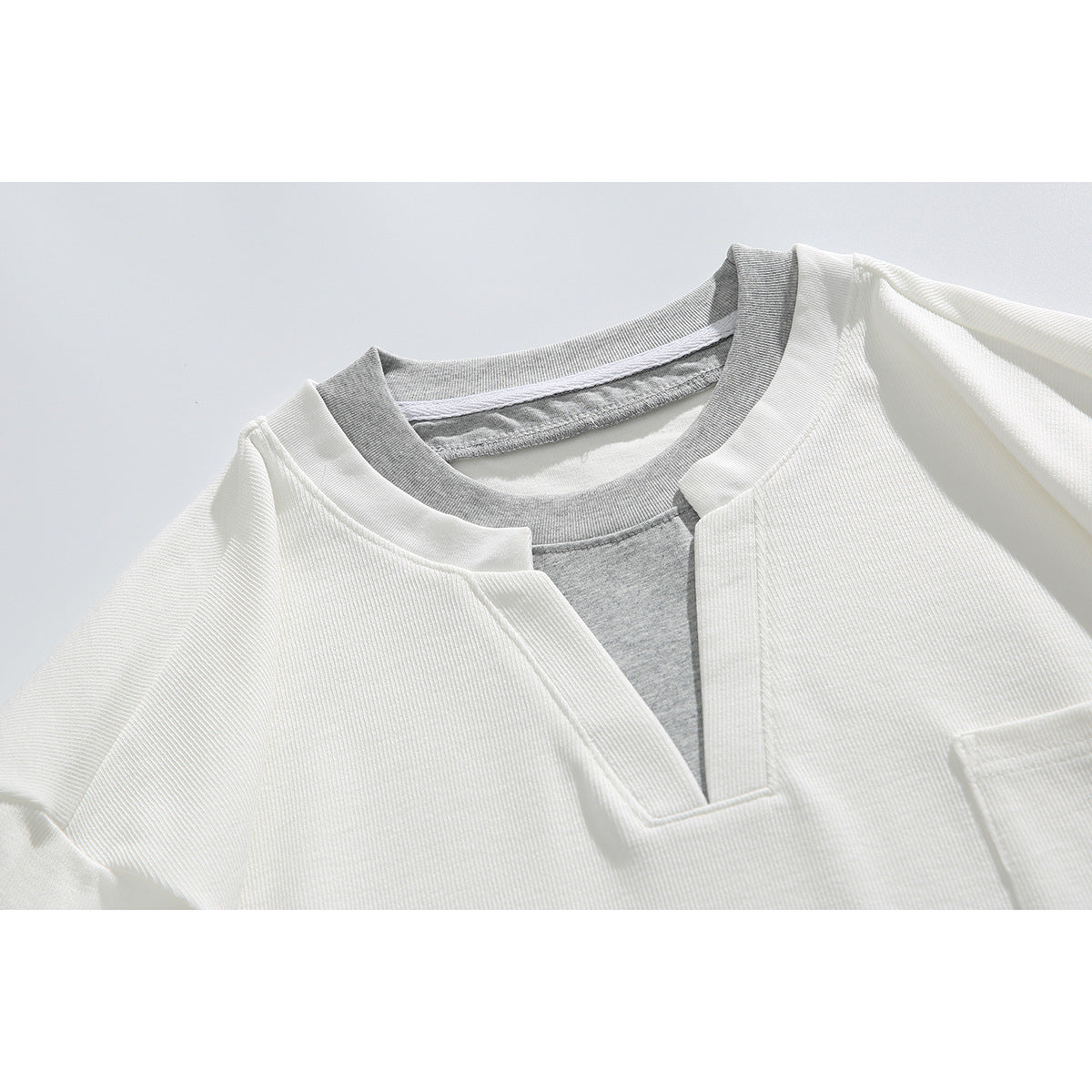 Close-up of a white ribbed short-sleeve shirt with a notched neckline layered over a gray crew-neck shirt.