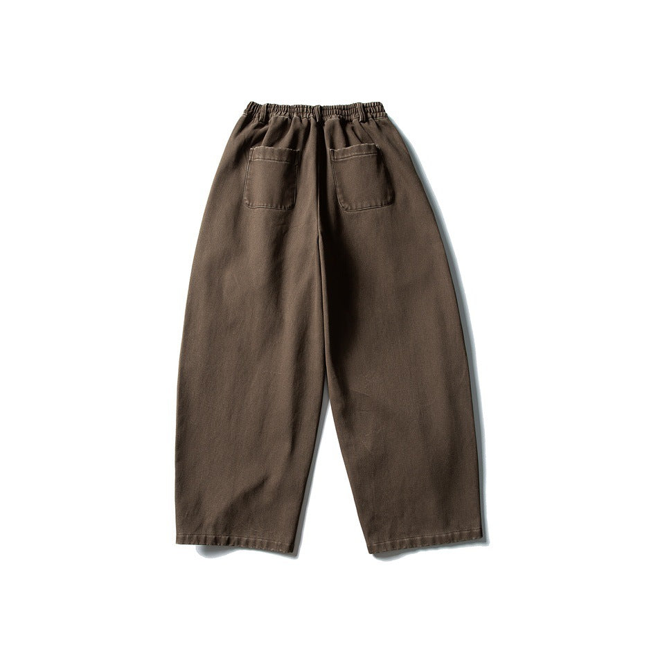 Back view of loose dark brown trousers with an elastic waistband and two patch pockets.