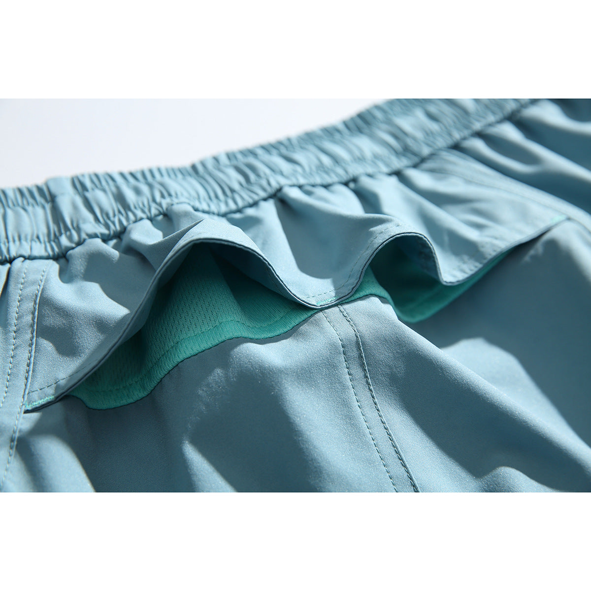 Close-up of light blue shorts showing the elastic waistband and turquoise mesh lining.