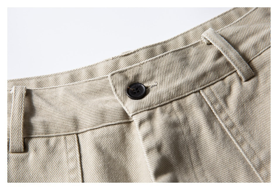 Close-up of beige shorts waistband with dark button, belt loops and stitching.