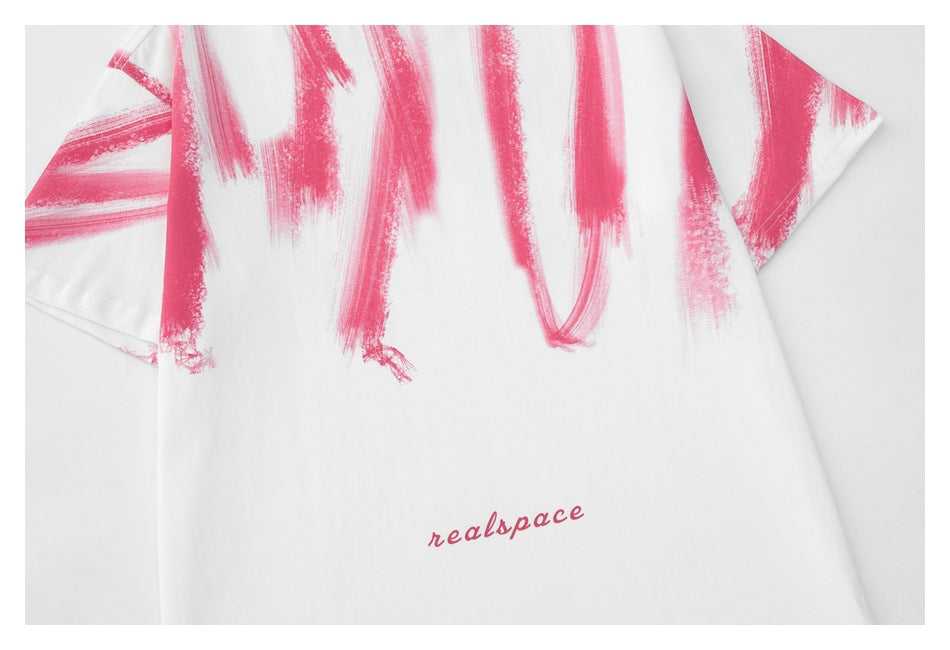 Front of a white short-sleeve T-shirt with pink brushstroke graphics and small pink “realspace” lettering.