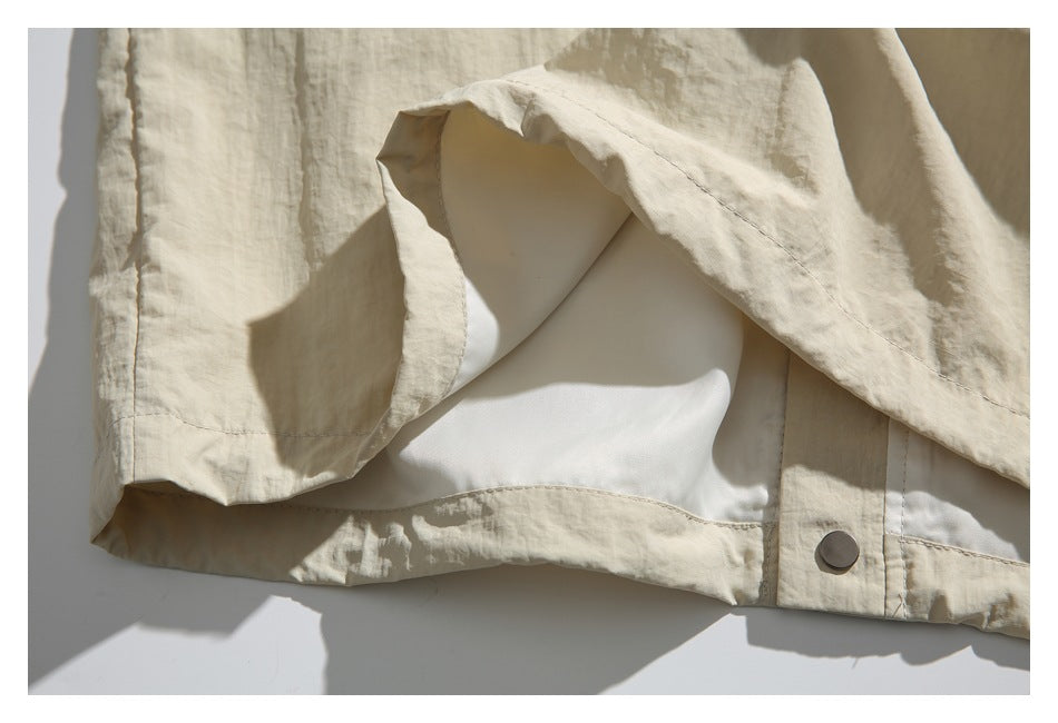 Close-up of an ivory garment opening, showing its pale lining, seam, and metal snap.