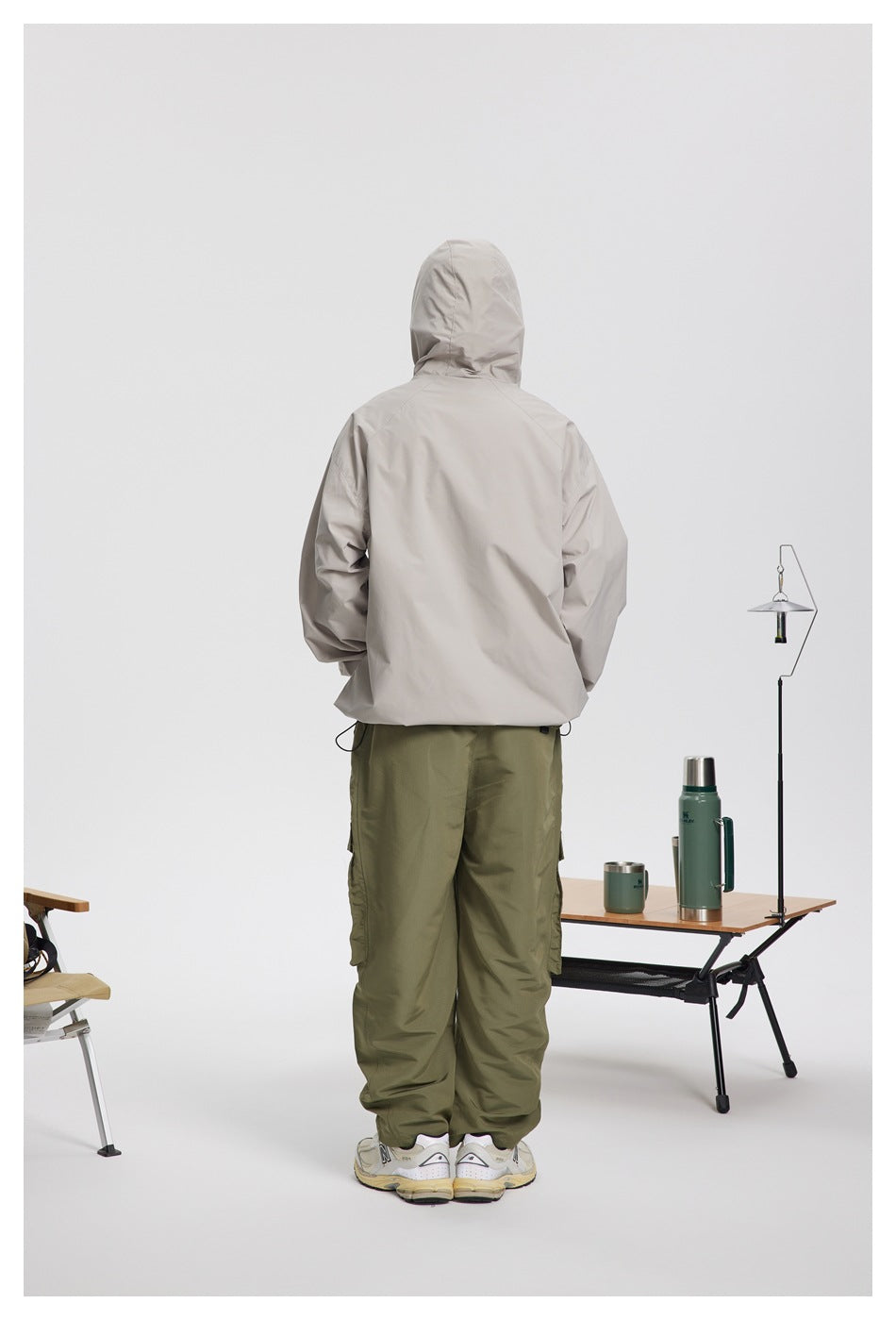 Rear view of a person wearing a light gray hooded jacket and olive cargo pants.
