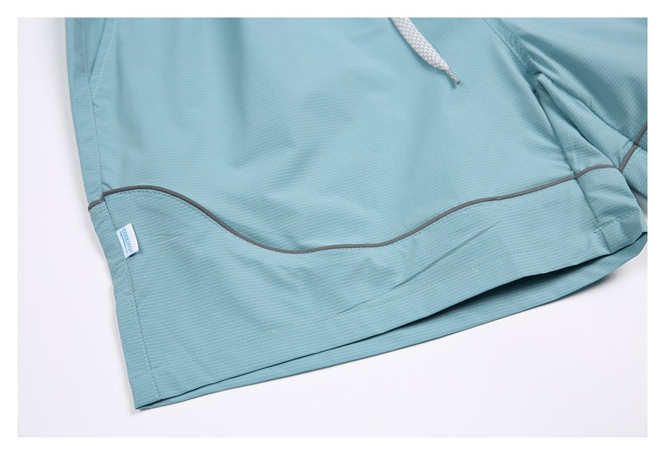 Close-up of aqua shorts showing the hem, gray piping, fine stripe texture and a small sewn-in label.