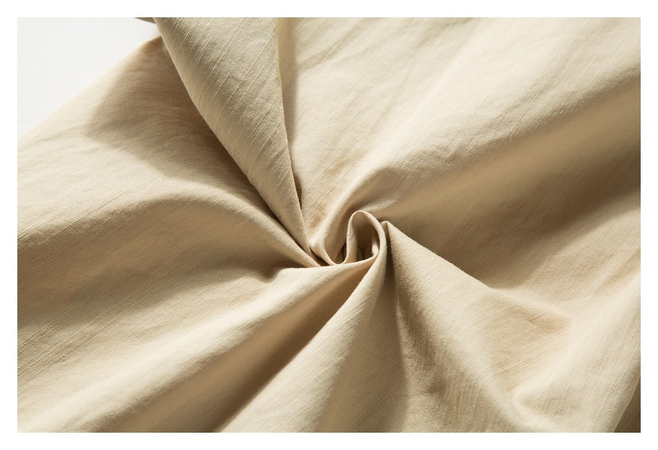 Close-up of beige fabric gathered into soft folds, showing its subtle woven texture.