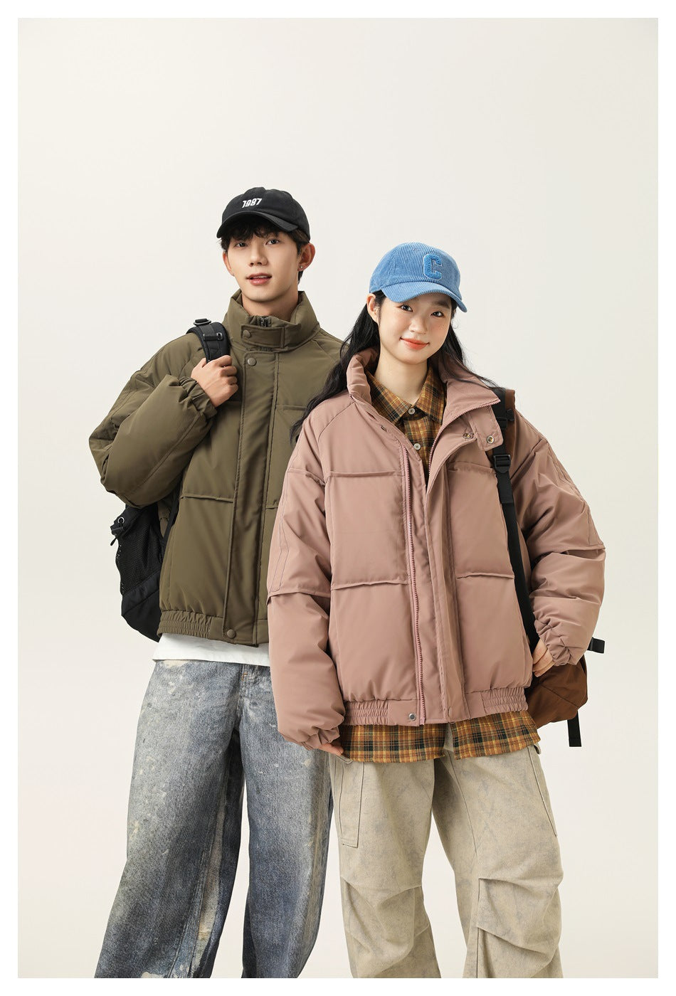Two models pose in olive green and dusty pink padded jackets with high collars, front closures and elastic hems.