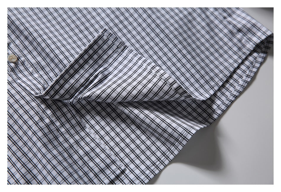 Close-up of a folded sleeve edge on the light shirt with a black plaid pattern.