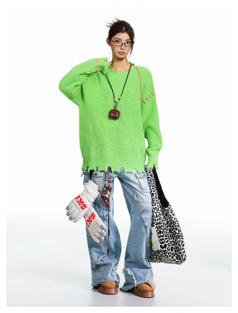 Model wearing a neon-green oversized sweater with pink stitch accents and a distressed hem.