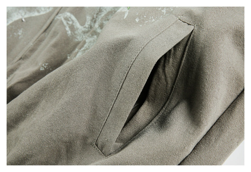 Close-up of a slanted welt pocket on textured gray-khaki fabric, with part of a white print visible behind it.