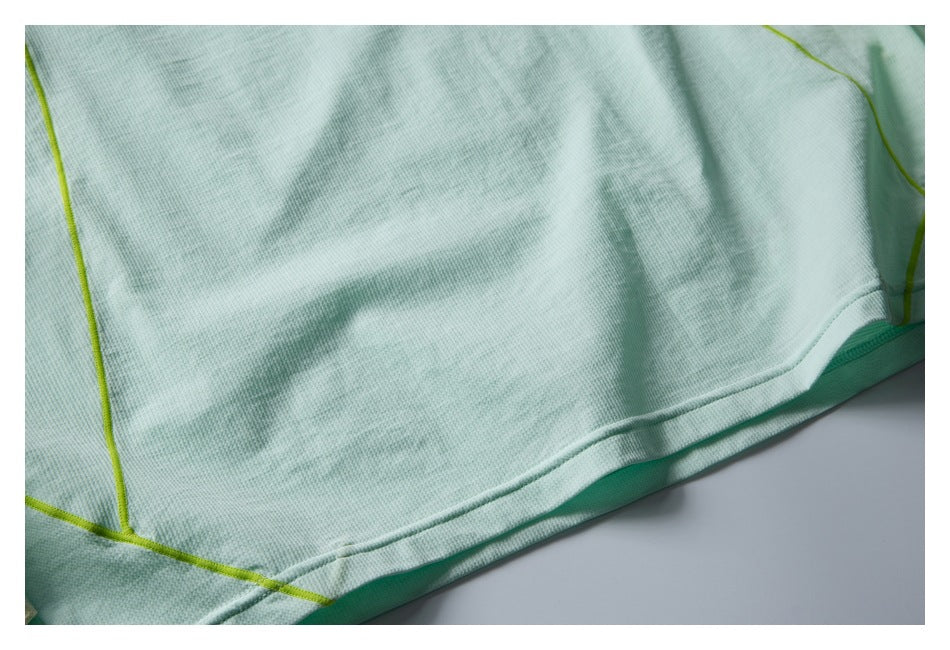 Close-up of the mint top's lower hem, fabric surface, and lime contrast seam.