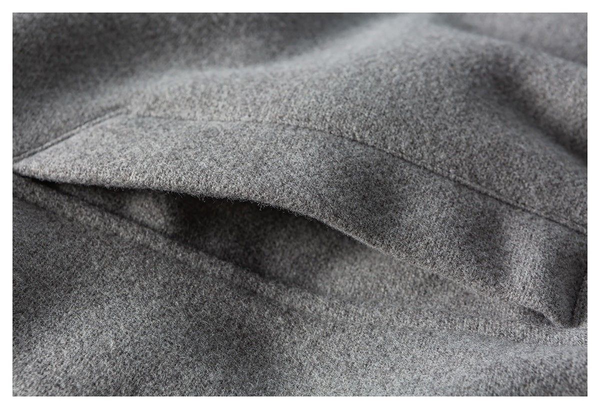 Close-up of a gray fabric pocket flap and its stitched edge.
