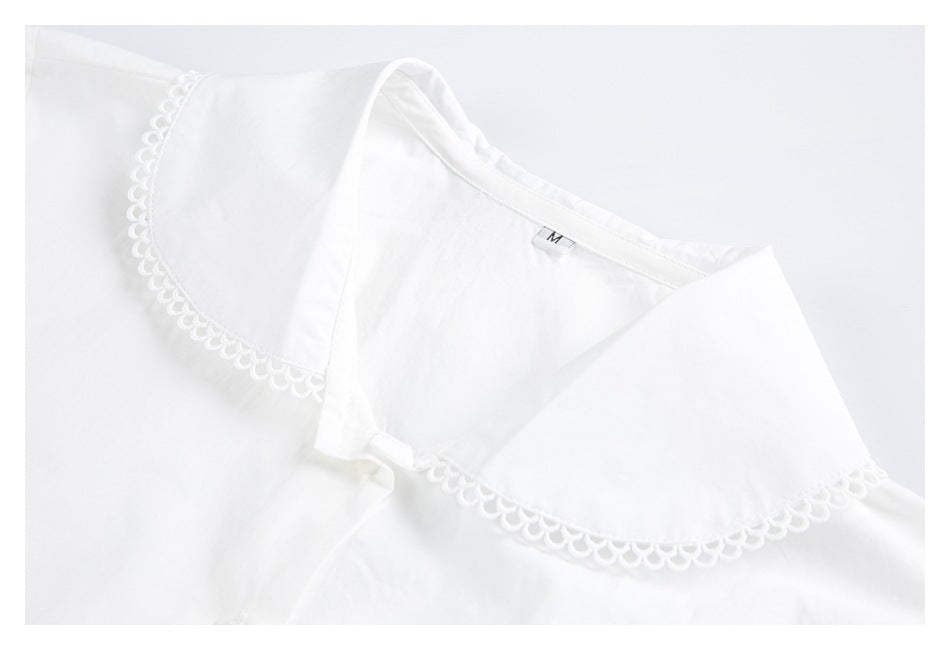 Close-up of a white shirt's wide rounded collar with scalloped trim and a small M size tag.