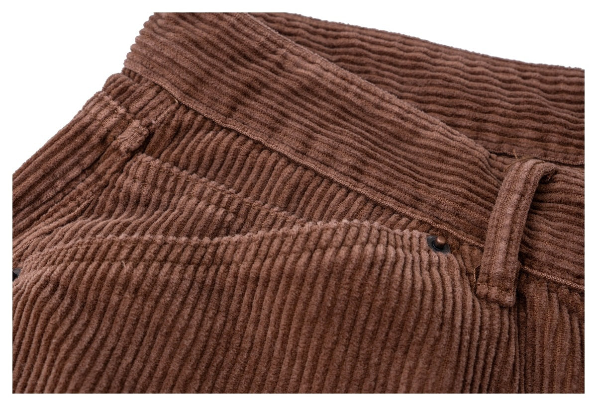 Close-up of brown corduroy trousers showing the waistband, belt loop, and a front pocket with a small dark rivet.