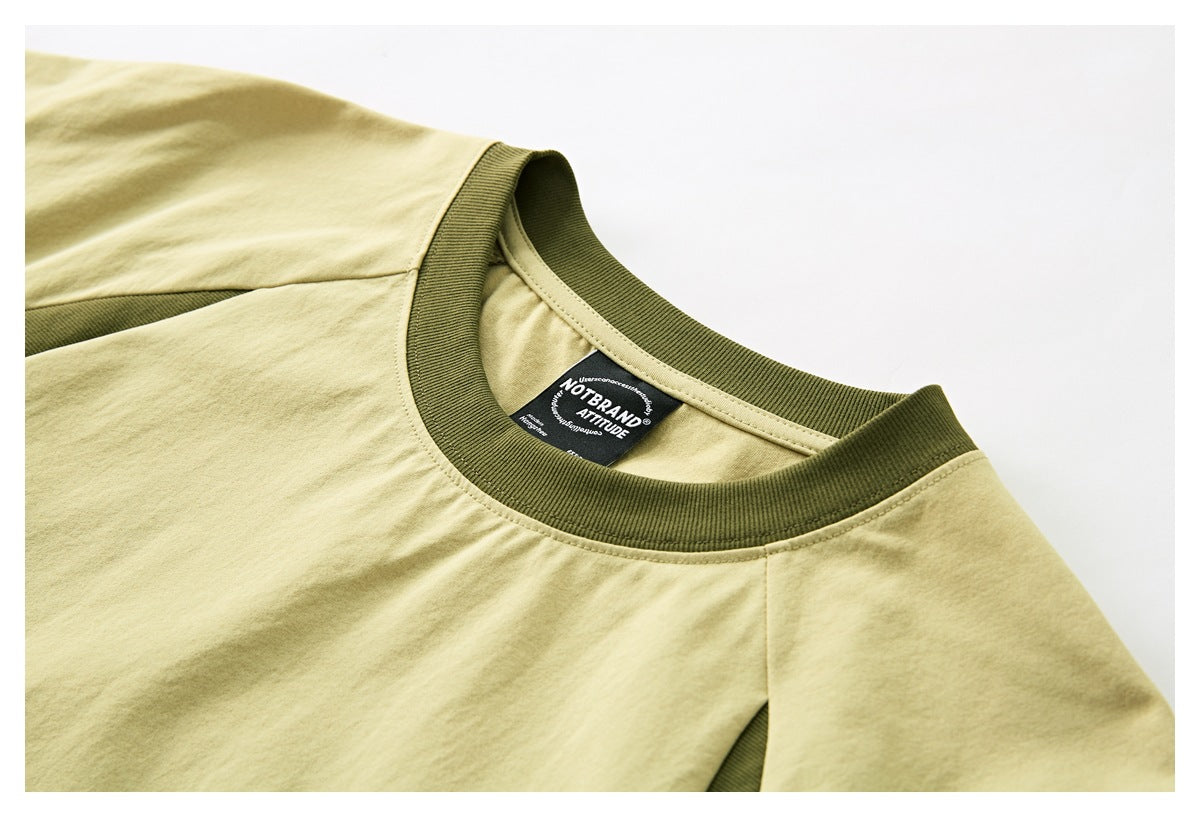 Close-up of a pale yellow T-shirt neckline with an olive ribbed collar and a black sewn-in neck label.
