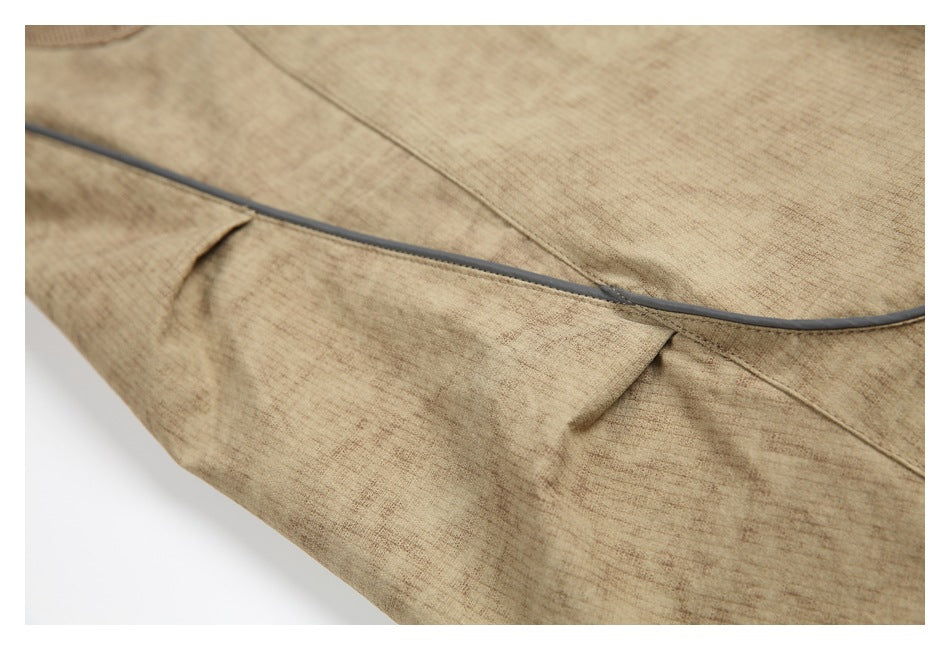 Close-up of gray piping and stitched seams on tan trousers.