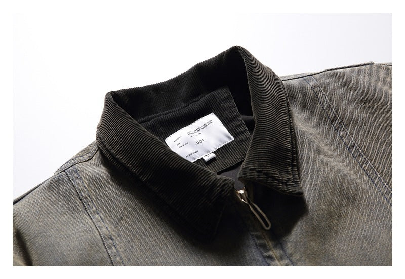Close-up of a gray-brown jacket collar with a black ribbed collar and zipper; a small inside label is visible.