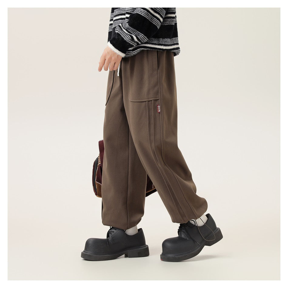 Side view of a model wearing loose brown cargo pants with a large side pocket and gathered hems.