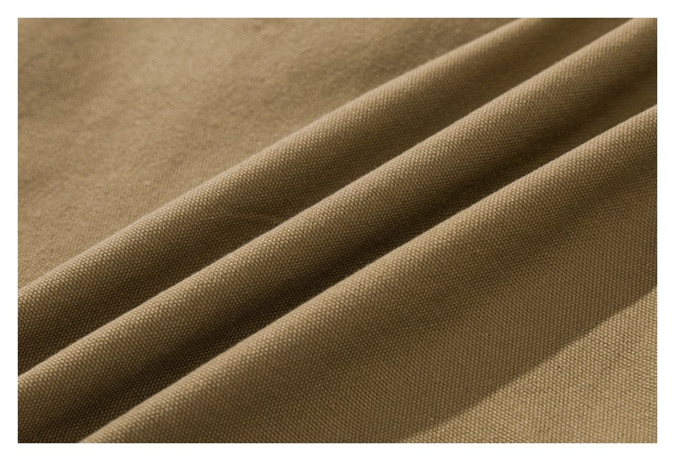 Close-up of tan-brown woven fabric arranged in soft folds, showing its fine textured surface.