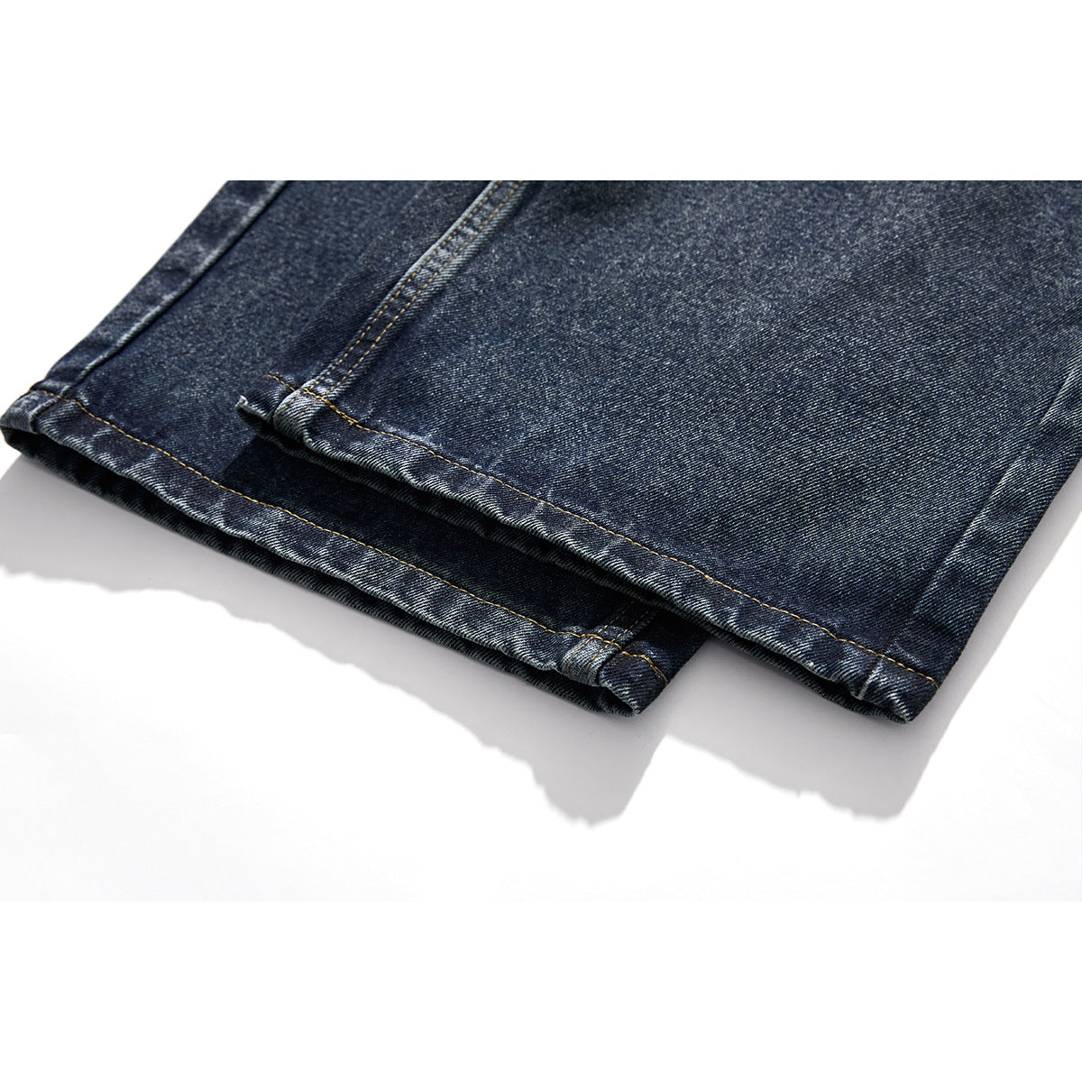 Close-up of dark blue jeans showing the folded hems and double-stitched seams.