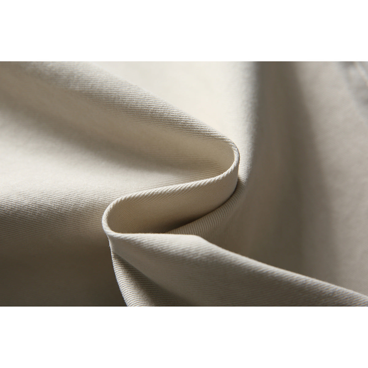 Macro view of folded light beige fabric with fine diagonal ribbing.