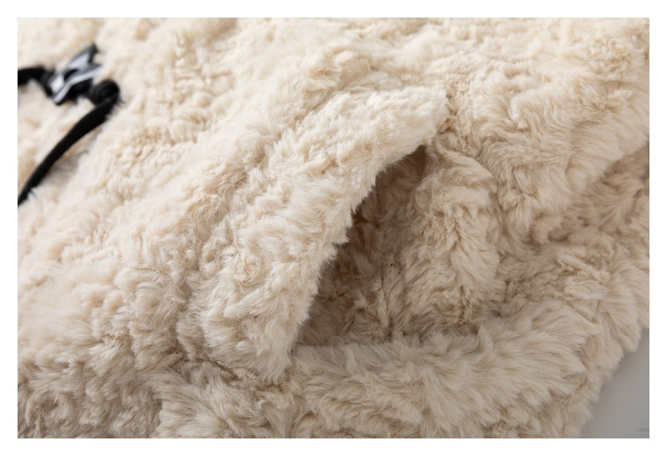 Close-up of cream shaggy fabric with a folded edge and a partial black tie visible.
