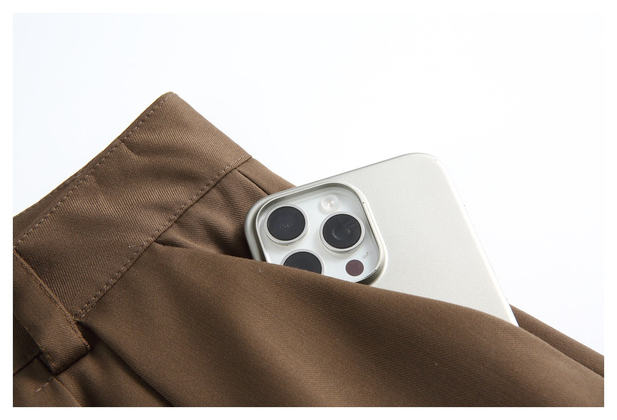 Close-up of a brown trouser pocket holding a white smartphone.
