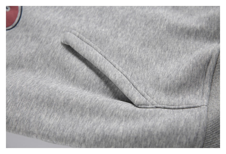 Close-up of the heather-gray hoodie’s angled front pouch pocket and ribbed side hem.