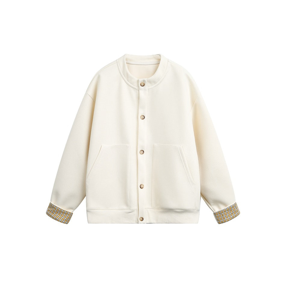 Beige button-front jacket with stand collar, two large front pockets and yellow plaid cuffs, flat lay