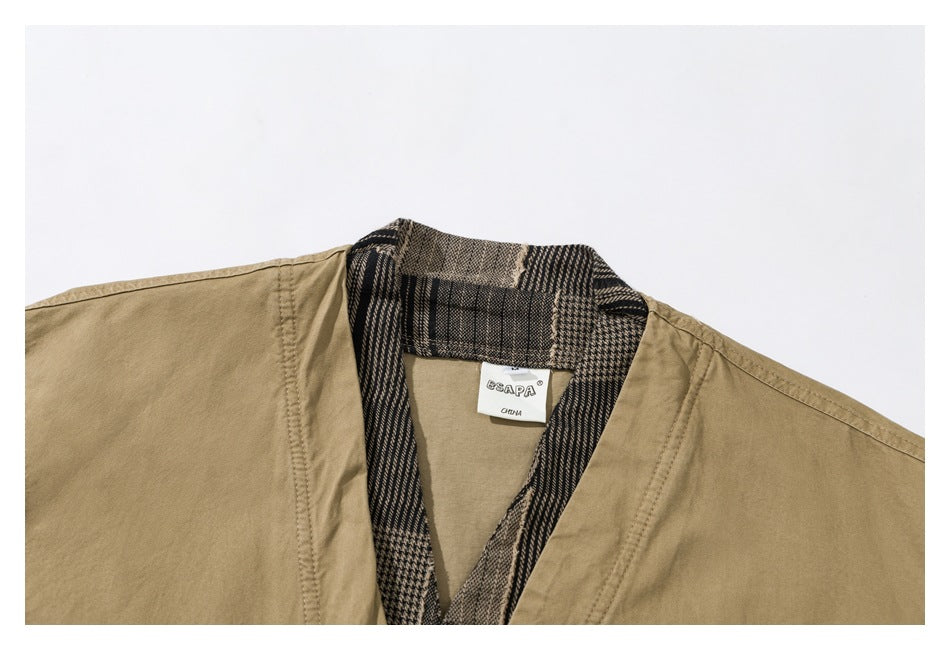Close-up of a khaki jacket collar with dark plaid trim and a sewn neck label.