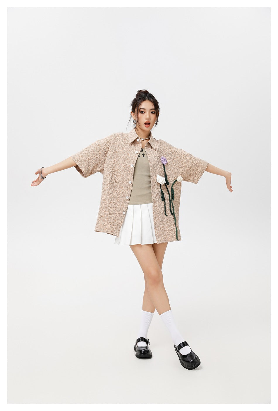 Model in the khaki floral textured short-sleeve shirt worn open with arms outstretched, showing crochet flowers