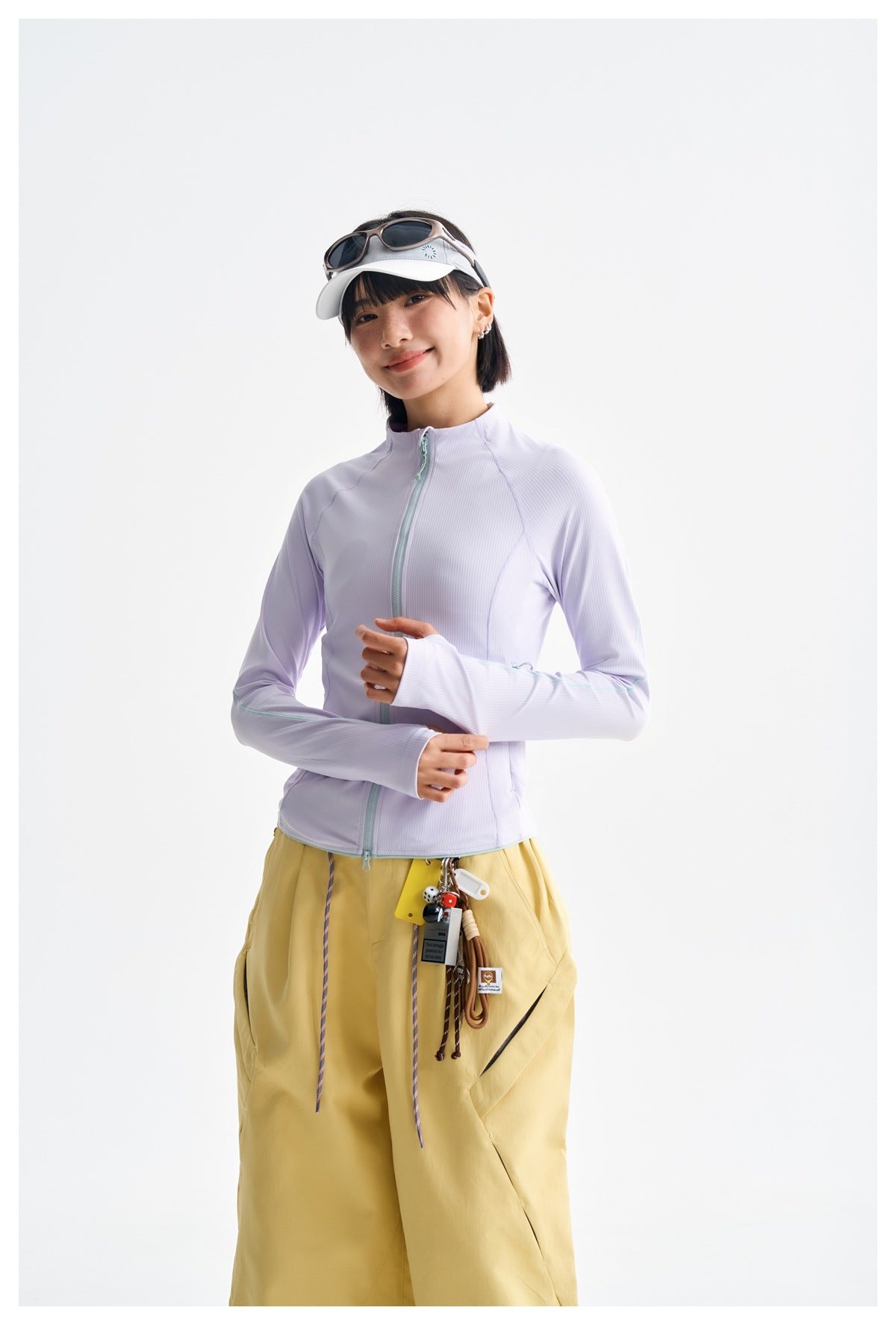Model wearing a pale lavender zip-front jacket with mint trim and loose mustard-yellow trousers.