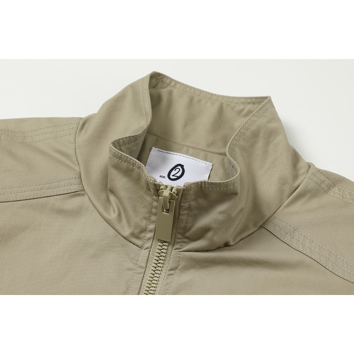 Close-up of a khaki jacket's stand collar, front zipper, stitching, and inner size label.