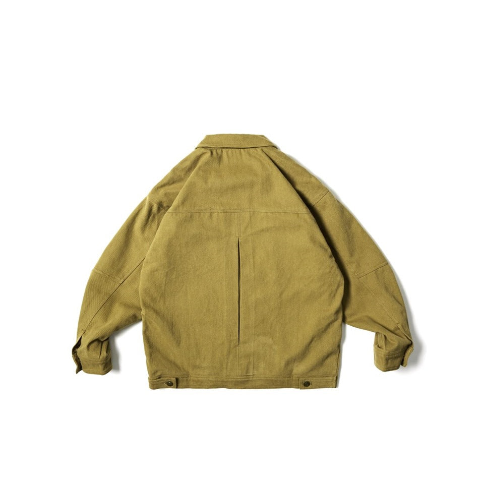 Back view of a mustard work jacket with a center pleat, panel seams, and snap-adjustable hem tabs.