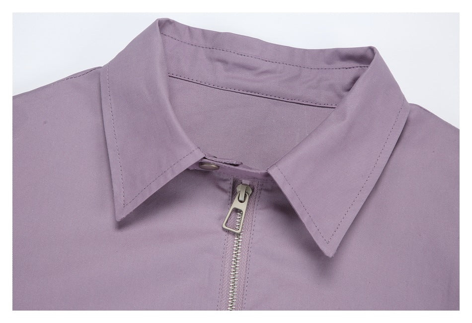 Close-up of a mauve garment's pointed collar and silver front zipper.