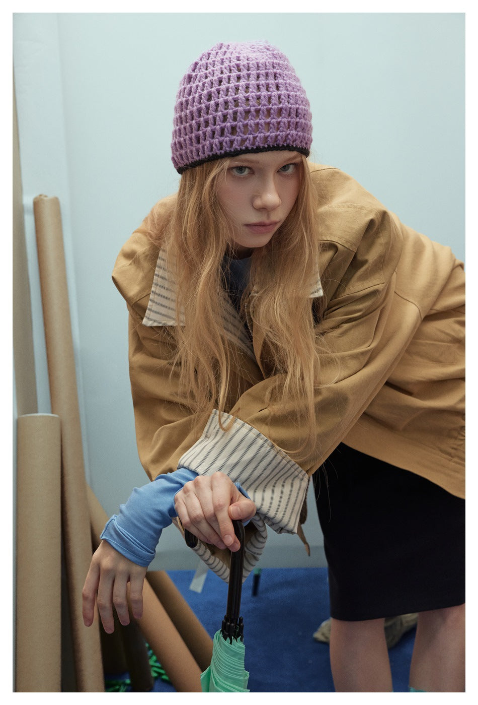 Model wearing an oversized tan jacket with a striped collar and turned-back cuffs.