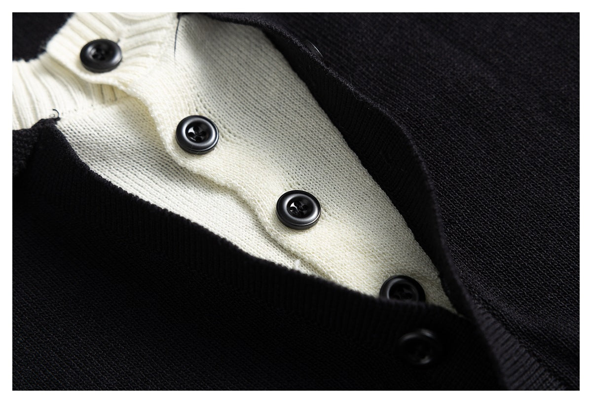 Close-up of a black knit garment with a cream-colored button placket and black buttons.
