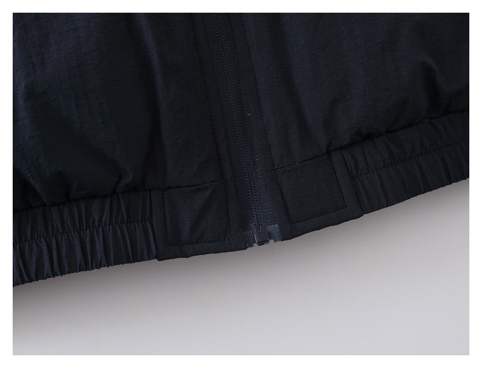 Close-up of a dark jacket hem with a central zipper and gathered elastic sides.