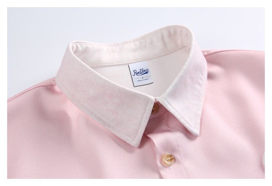 Close-up of the shirt's pale pink fabric, white collar, tan buttons, and sewn neck label.