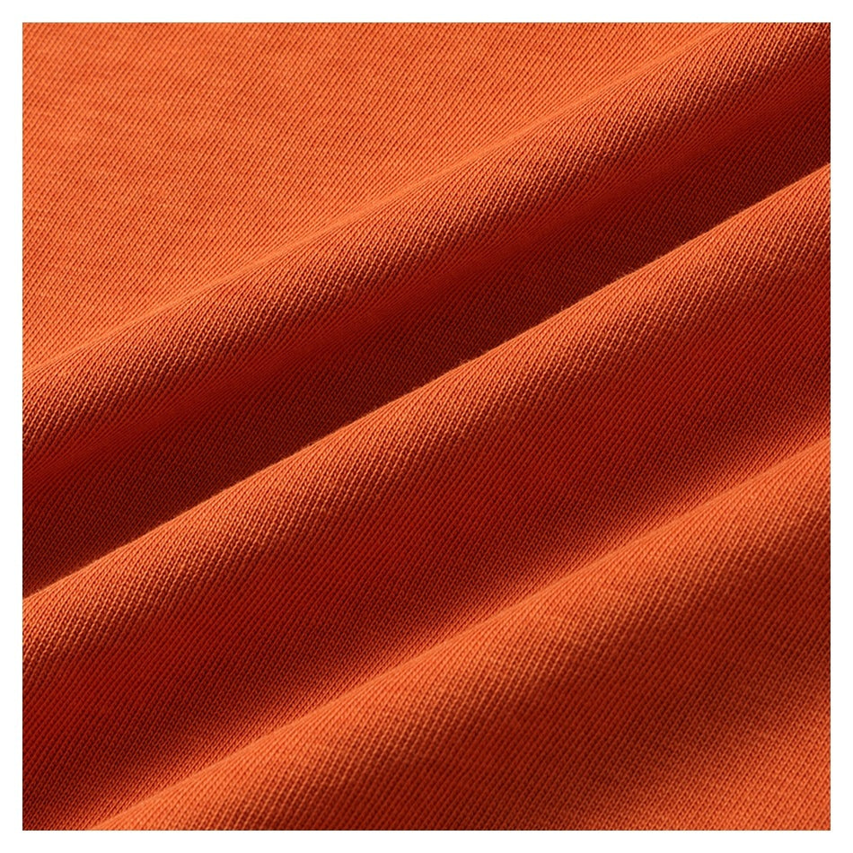 Macro view of orange knit fabric arranged in soft diagonal folds.