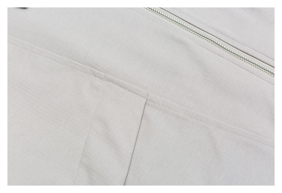 Close-up of the light gray jacket's front zipper and stitched panel seams.