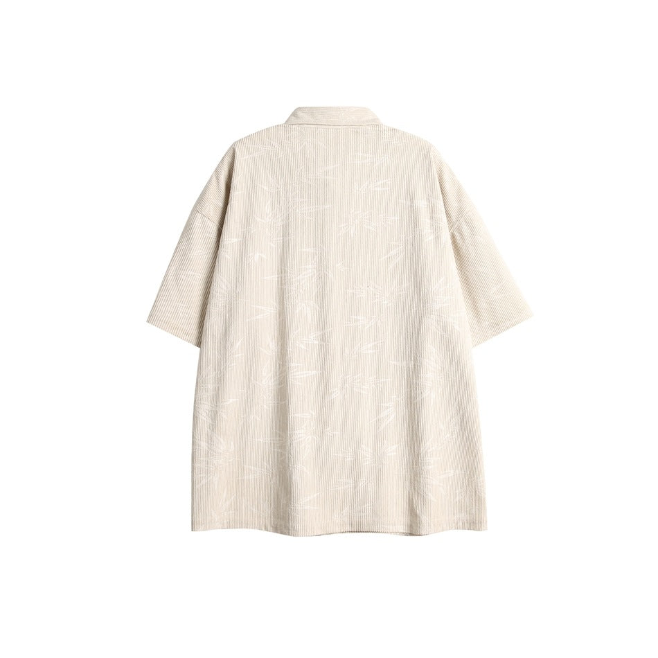 Back view of a light cream oversized short-sleeve collared shirt with a subtle tonal pattern.