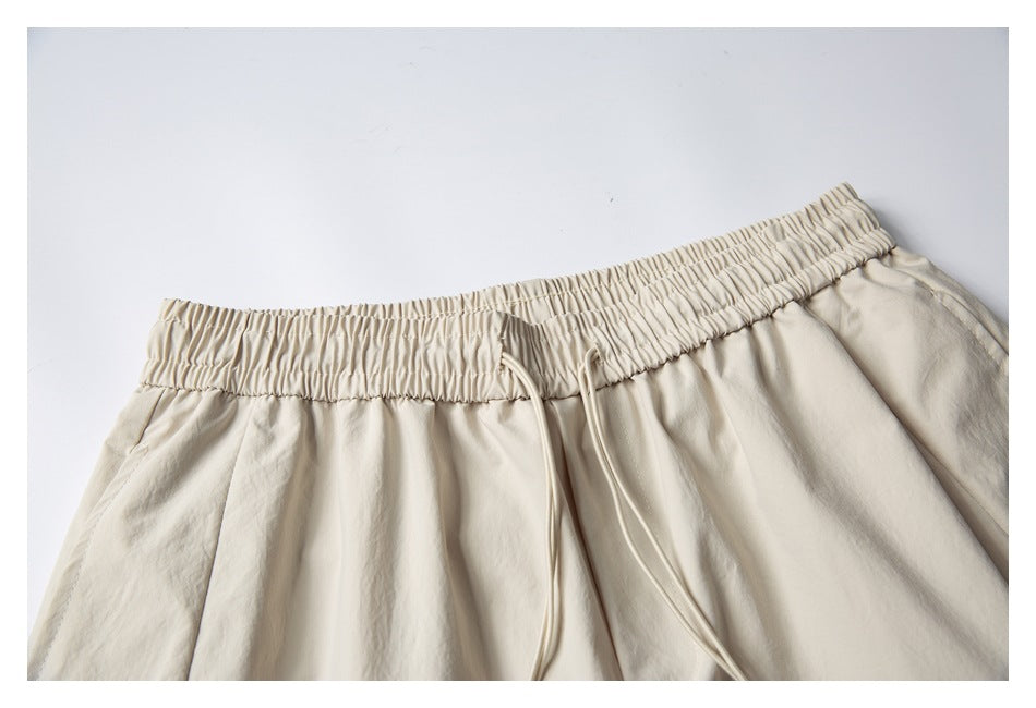 Close-up of the light beige shorts' gathered elastic waistband and long drawstrings.