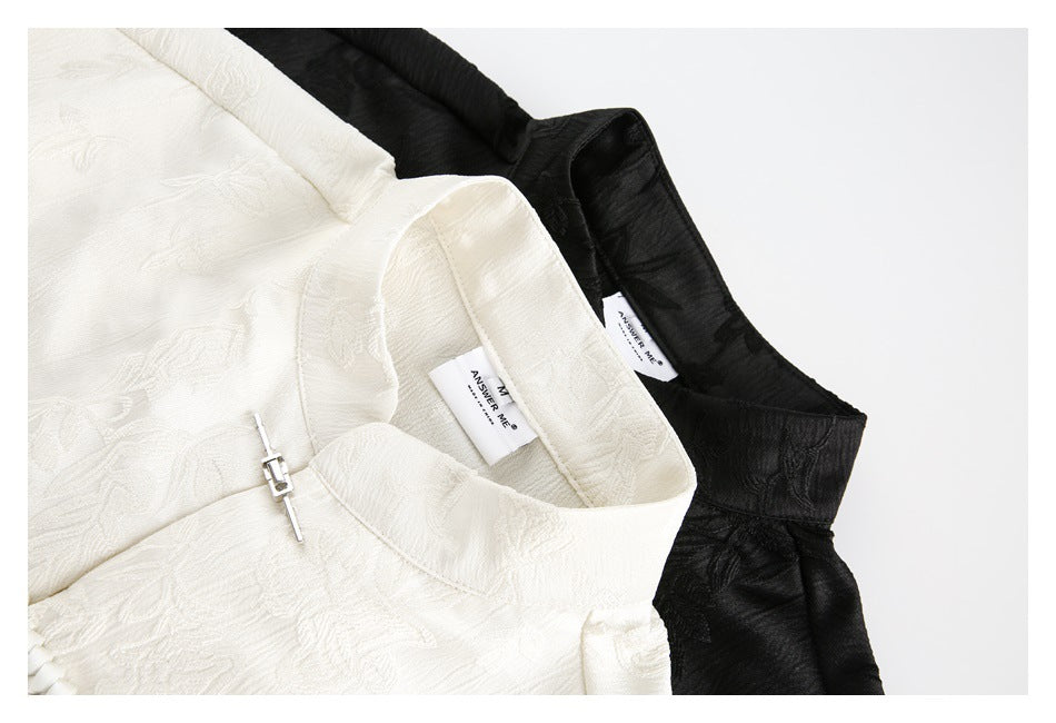 Close-up of ivory and black shirt collars, showing the mandarin neckline and a metal clasp.
