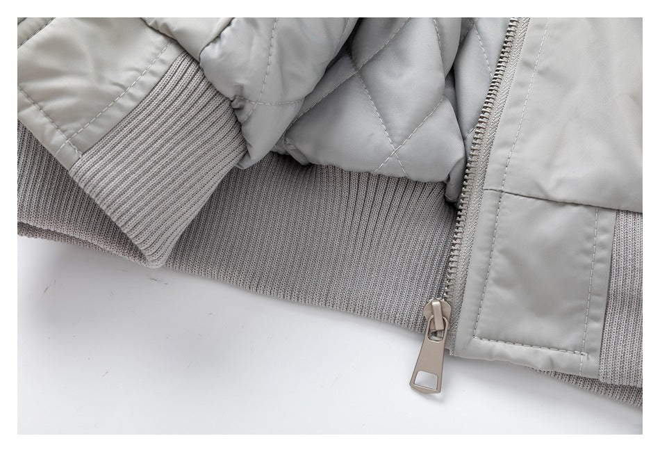 Close-up of the light gray jacket's ribbed knit hem and cuff beside the zipper.