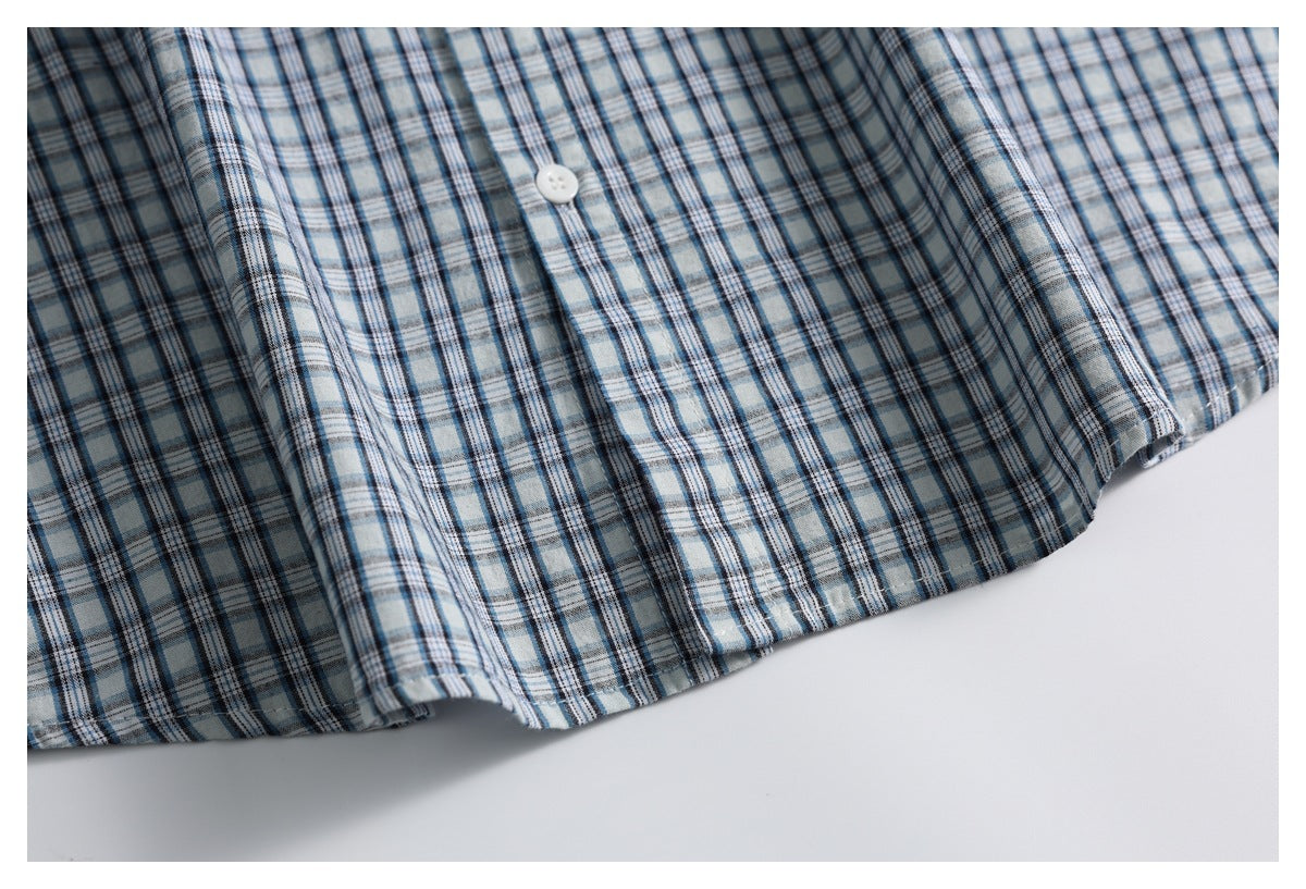 Close-up of the blue plaid shirt front, showing a white button and stitched lower edge.