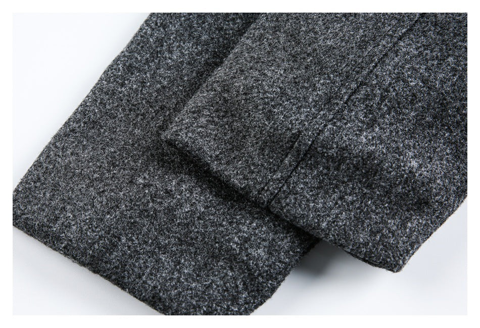 Close-up of overlapping charcoal-gray coat panels with a folded edge and visible stitching.