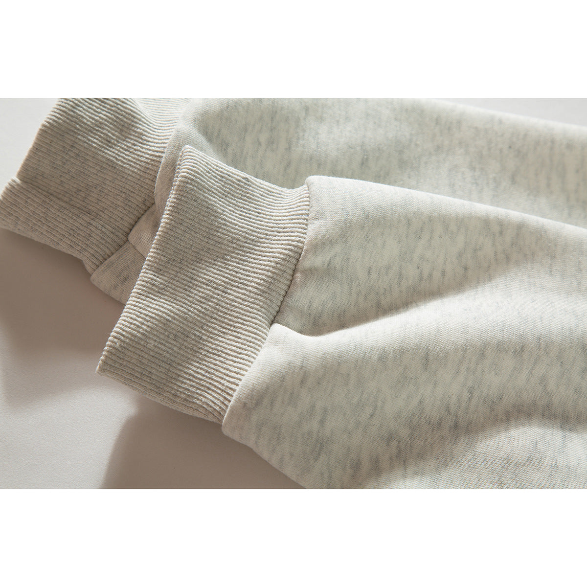 Close-up of the off-white sweatshirt sleeve showing its wide ribbed cuff.