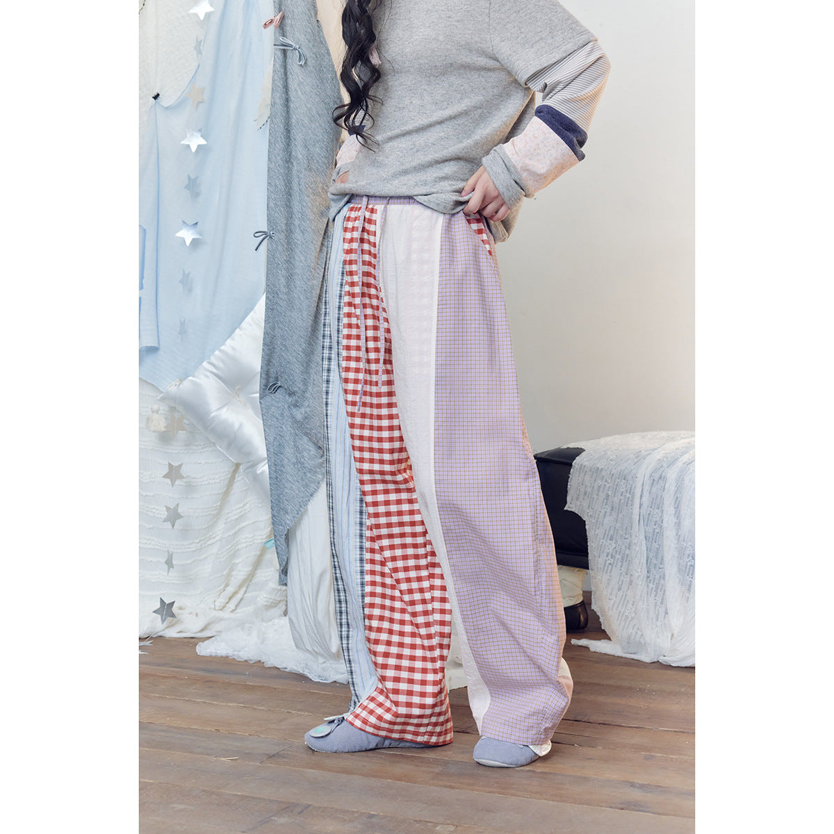 Cropped front view of a model wearing wide patchwork trousers with gingham, striped, checked and white panels.