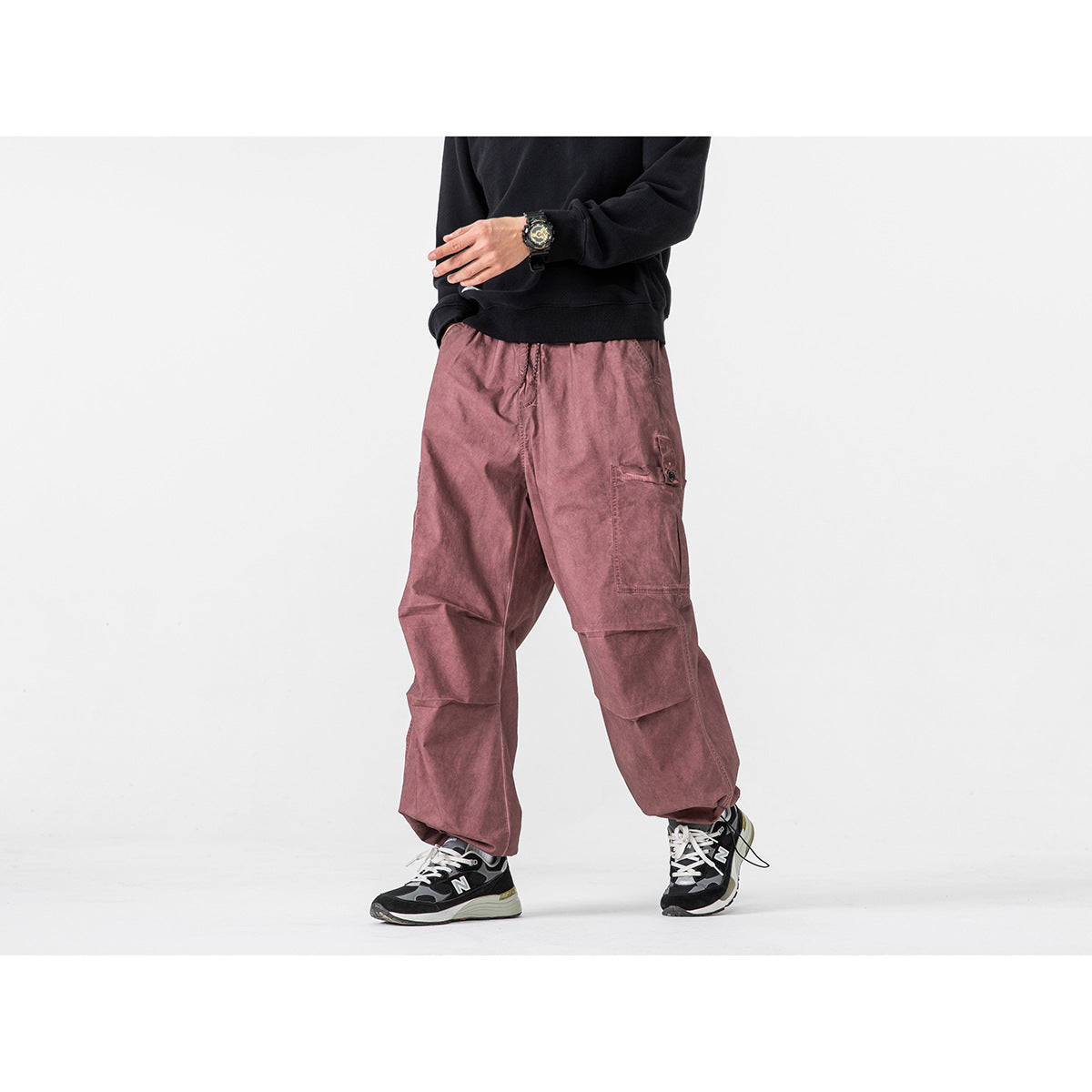 Model wearing dusty rose wide-leg cargo pants with oversized flap pockets and a black sweatshirt.