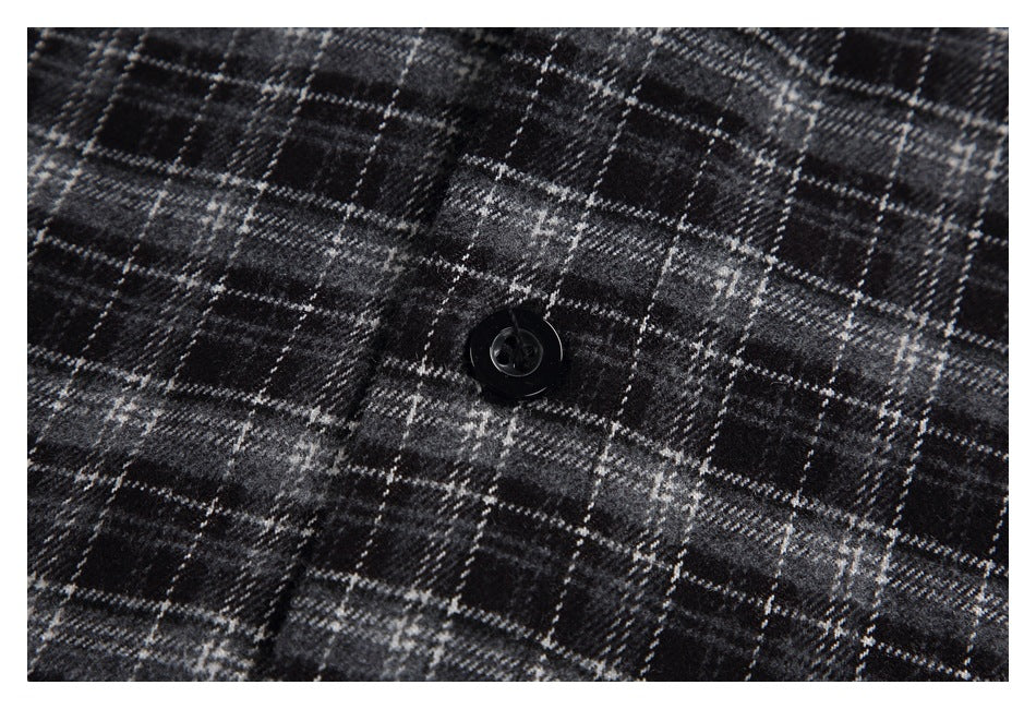 Close-up of a black button on black-and-gray plaid fabric.